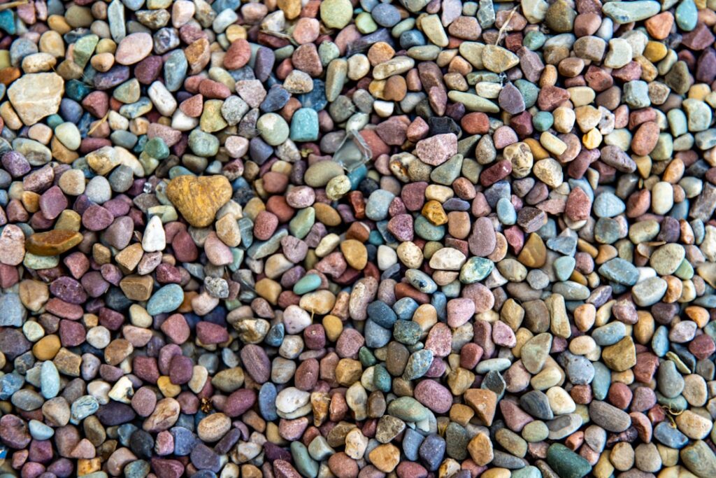 Close-up of a hand carefully placing a layer of small pebbles at the bottom of a clear glass terrarium container