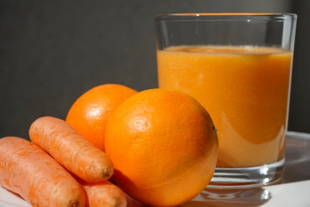 A close-up shot of hands blending steamed carrots and ripe banana in a bowl to create a smooth mask paste