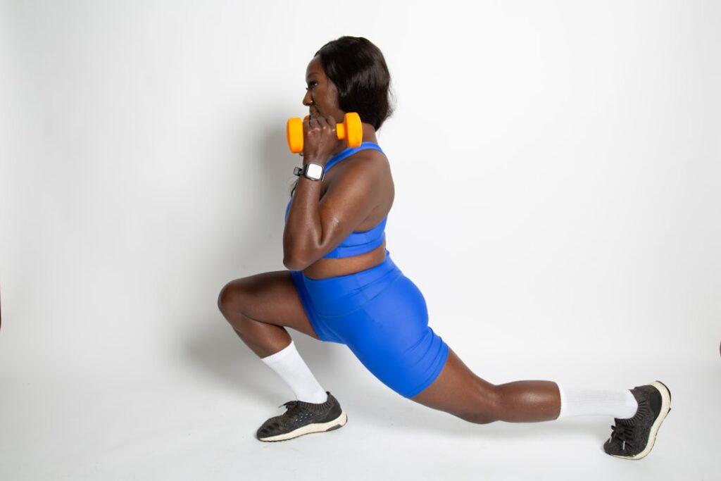 A person demonstrating perfect form for a dumbbell lunge showcasing a quad-dominant movement