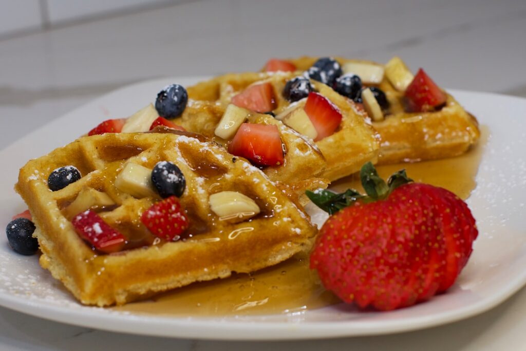 A stack of freshly made golden vegan waffles crispy on the outside and fluffy inside with steam gently rising garnished 