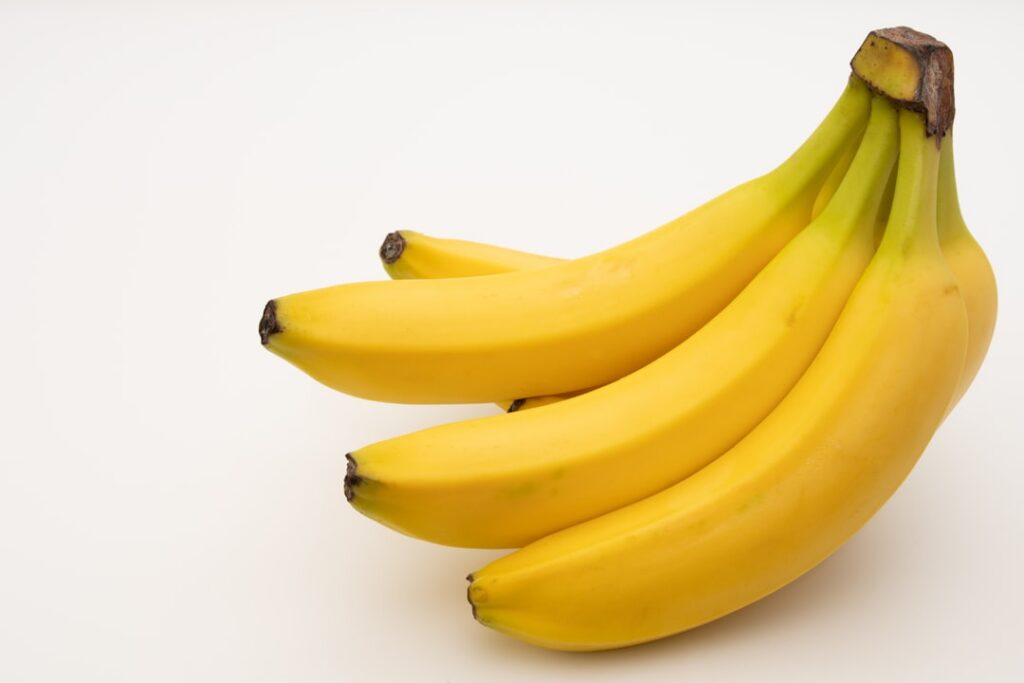 Close-up of a bowl with a creamy banana and honey mask with a fresh banana and a honey dipper nearby