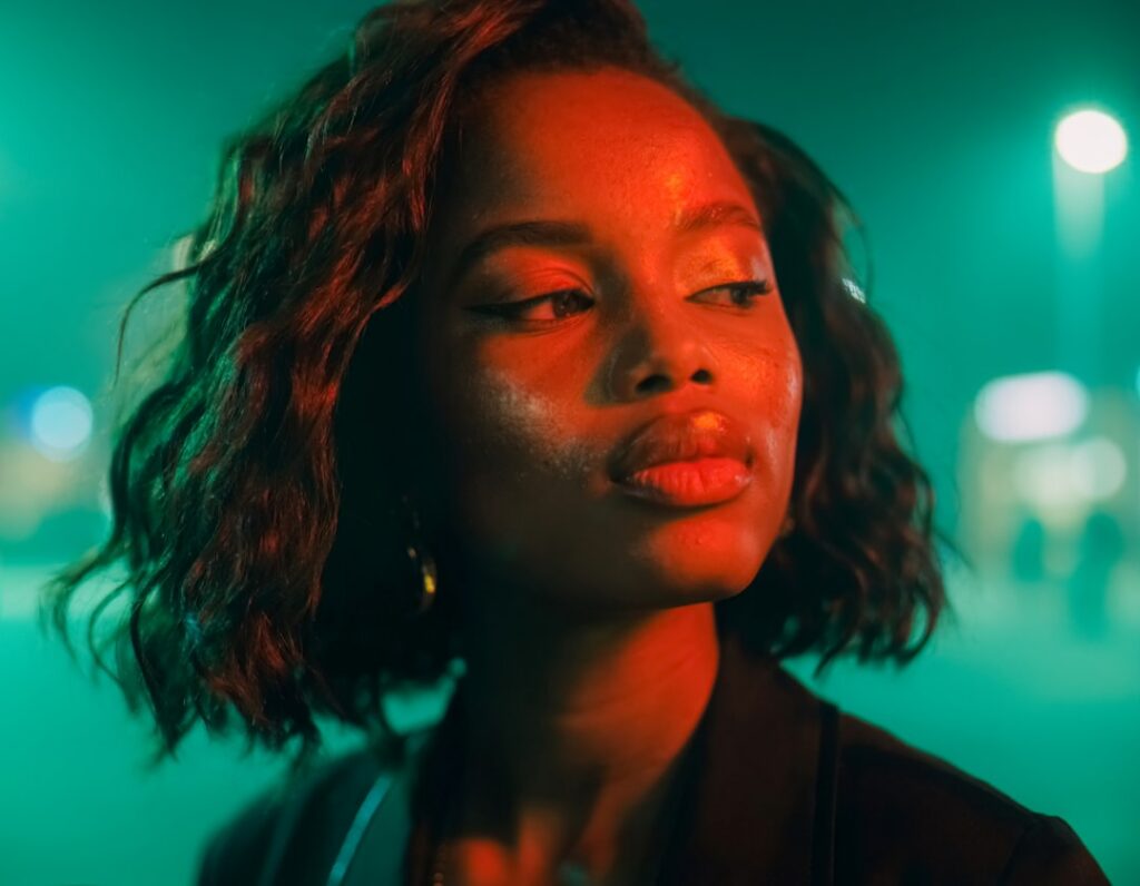 A woman applying a clear light-colored gel to her face at night in a soft natural setting