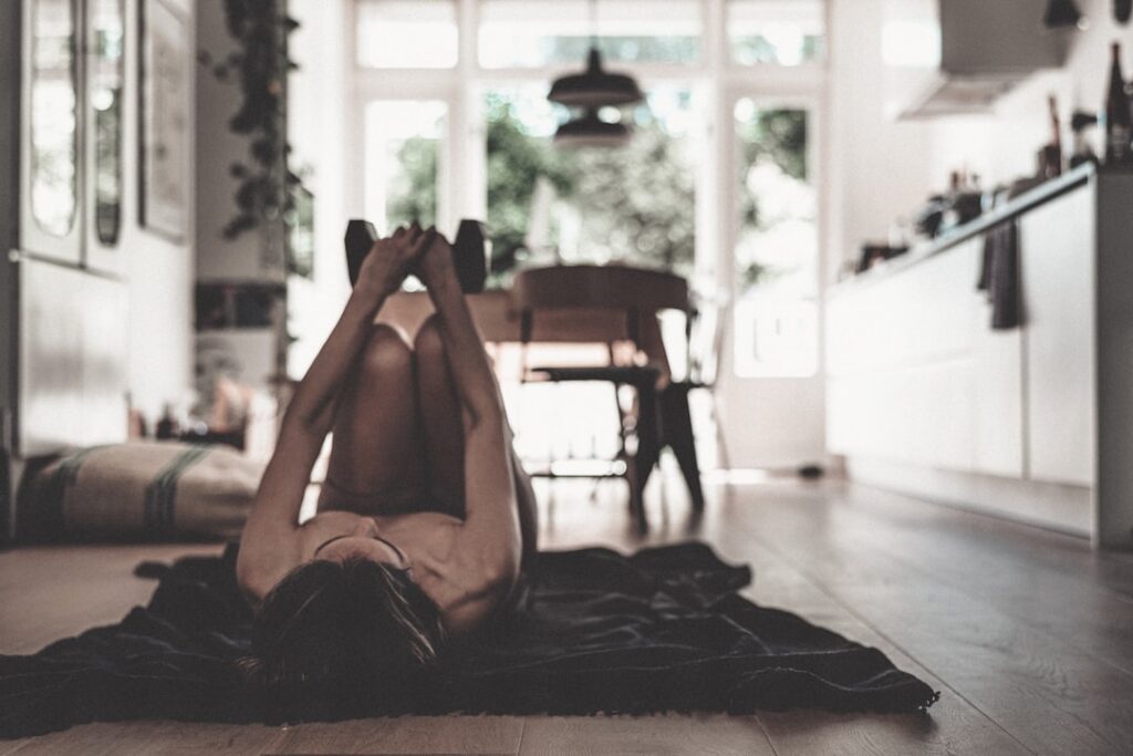 A woman doing a bodyweight squat in a bright clean home environment demonstrating good form and an energetic pose