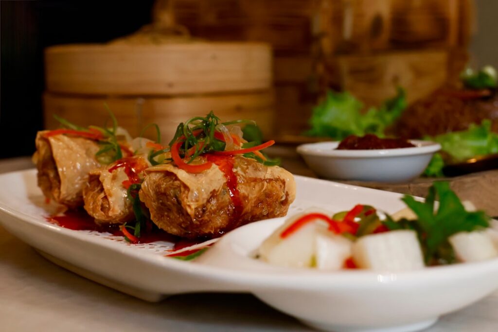 A beautiful platter of assorted fresh vegan spring rolls with various colorful fillings and a small bowl of peanut dippi