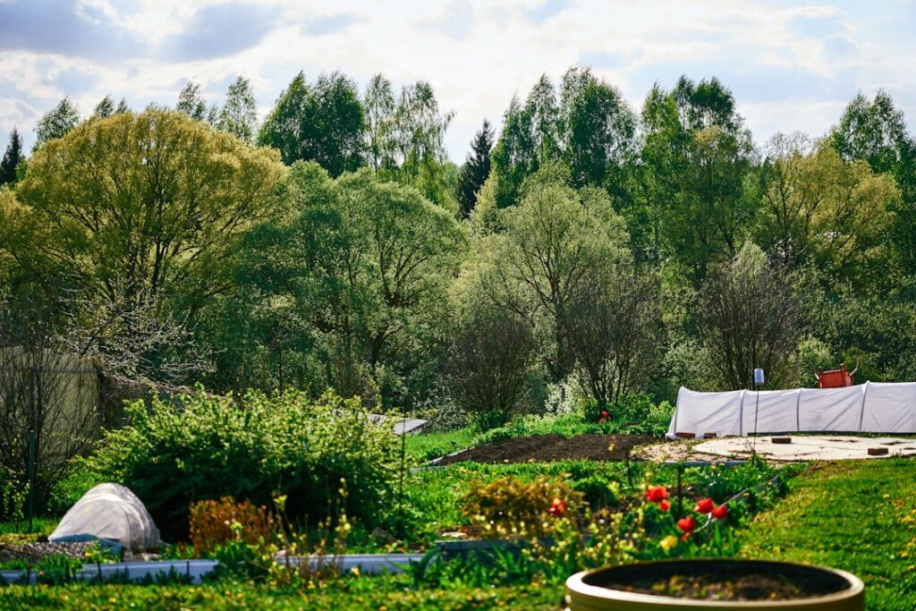 A vibrant garden bed with various crops partially covered by different types of garden covers like row covers netting an