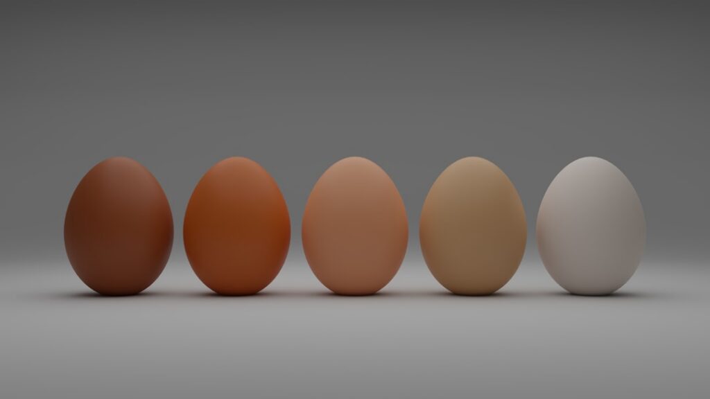 A trio of eggs one brown one white and one pasture-raised egg perhaps with a slightly deeper yolk color displayed side-b