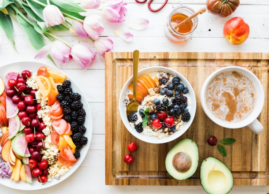 A colorful array of fruits vegetables and lean protein sources that are beneficial for blood pressure along with a glass