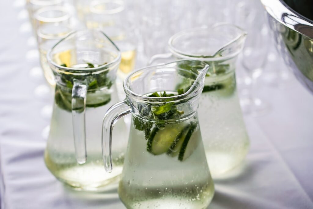 A clear glass filled with refreshing cucumber and mint infused water garnished with fresh cucumber slices and mint leave