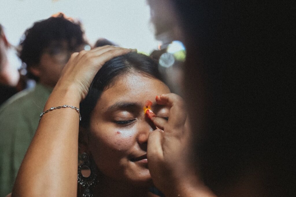 A beautiful woman with glowing clear skin gently applying a natural facial oil perhaps with visible hints of turmeric or