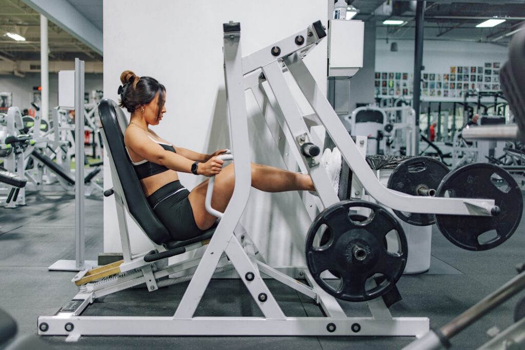 A woman performing leg extensions on a machine demonstrating focus and good form
