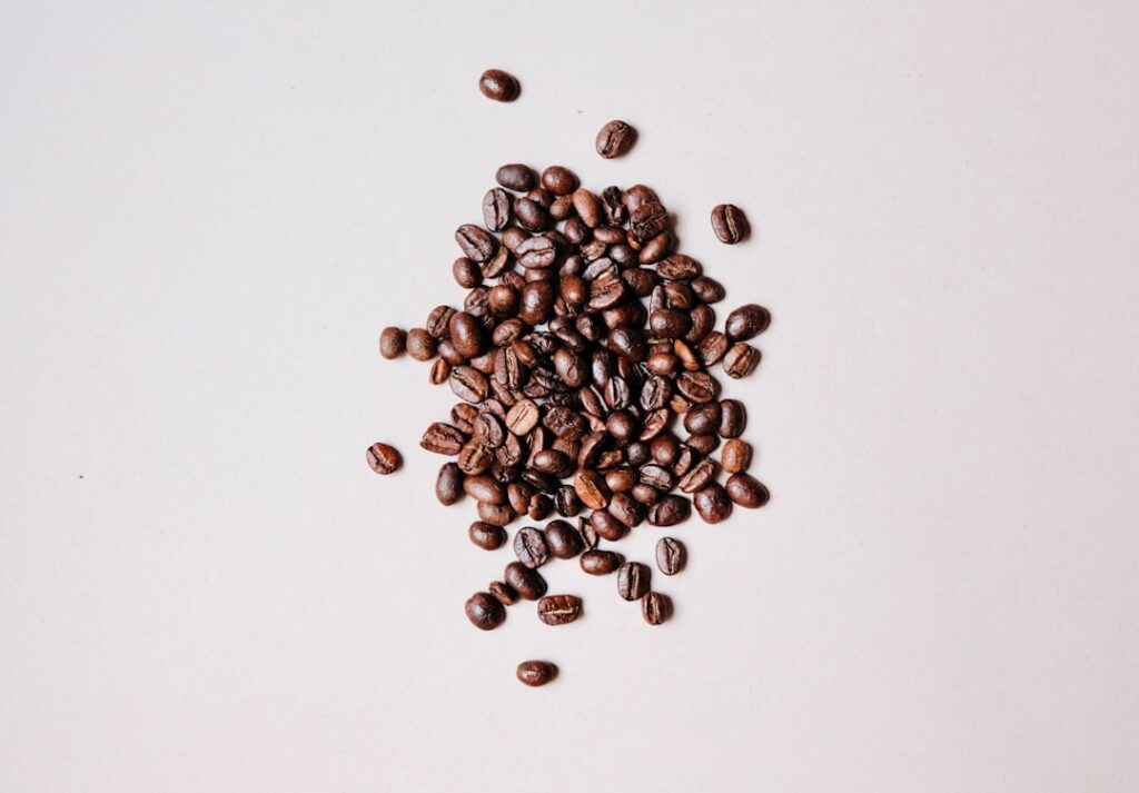A close-up shot of rich dark coffee beans next to a homemade shampoo bottle suggesting the natural ingredients Focus on