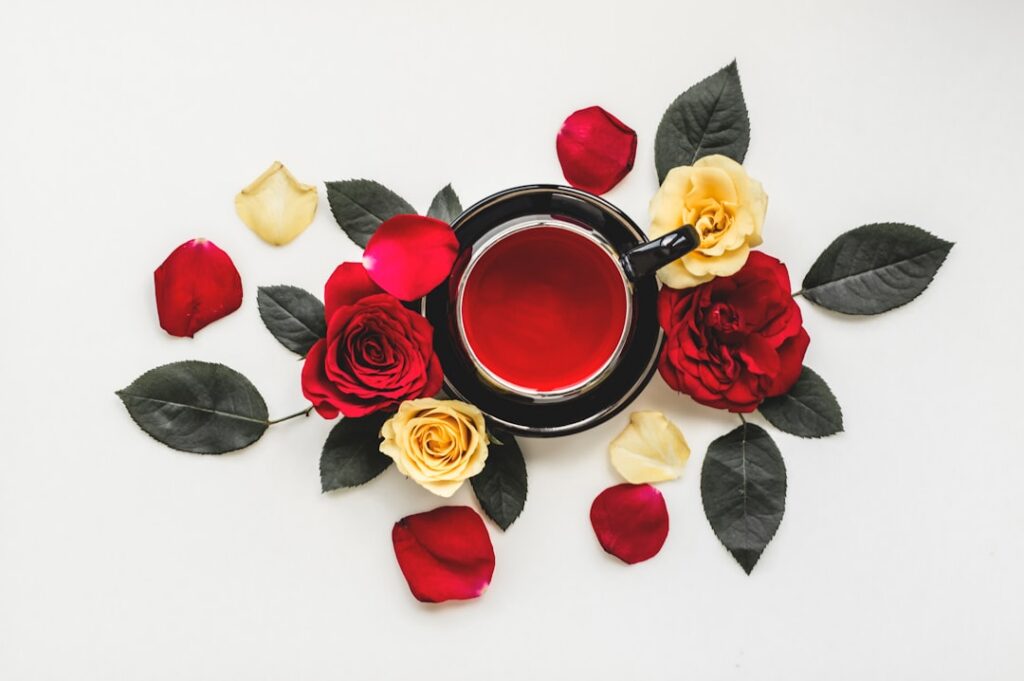 A close-up shot of fresh rose petals and a bowl of bright yellow turmeric powder perhaps with a small bottle of rose wat