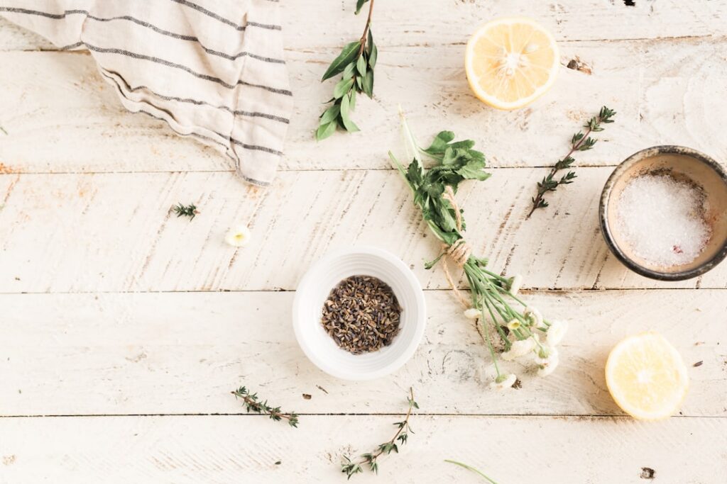 A beautiful flat lay image showing fresh lemons dried cloves and a bottle of baby oil with a small mixing bowl or jar su