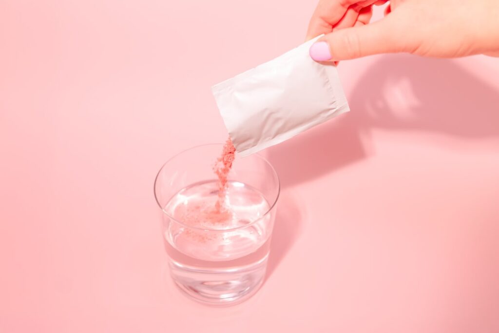 A vibrant fresh collagen drink shot in a small glass surrounded by ingredients like collagen powder fresh berries strawb