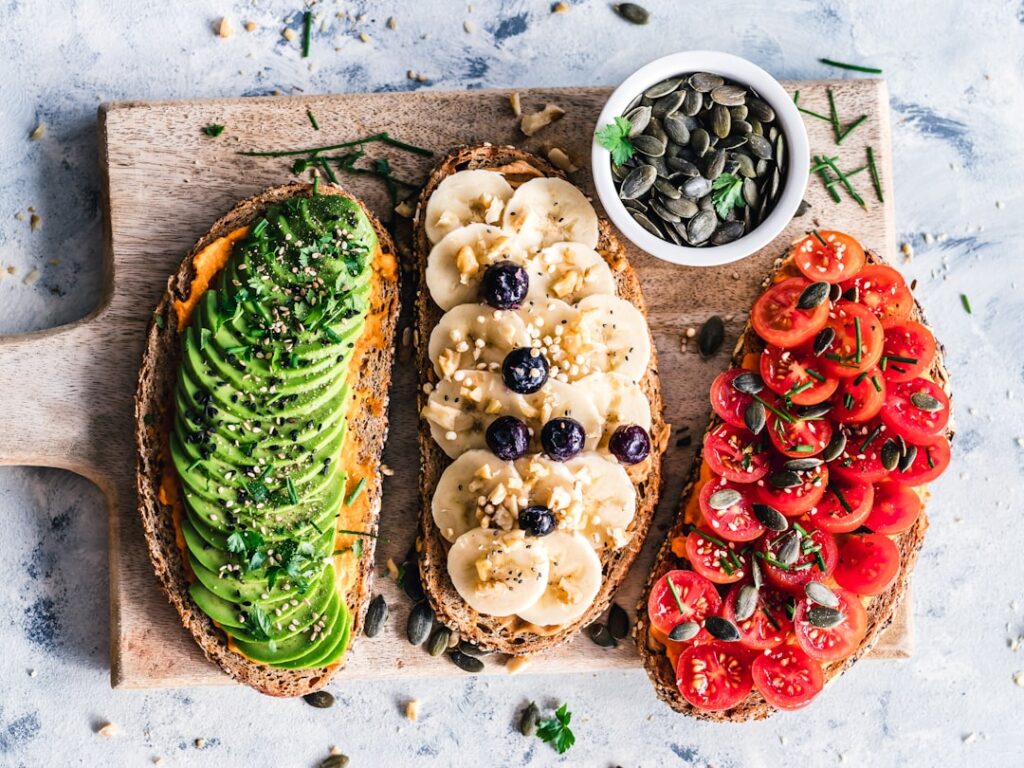 A beautifully garnished slice of vegan avocado toast on whole-grain bread topped with cherry tomatoes microgreens sesame