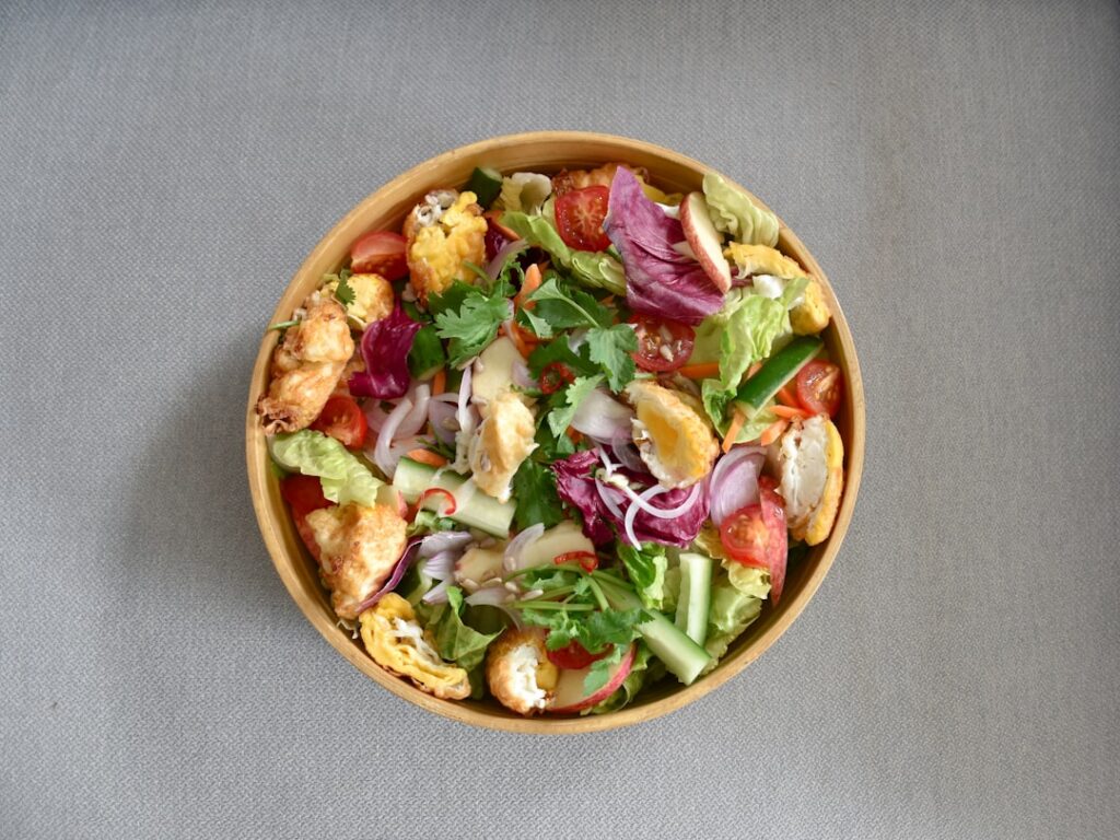 A vibrant close-up shot of an avocado tomato and corn salad in a rustic bowl garnished with fresh herbs
