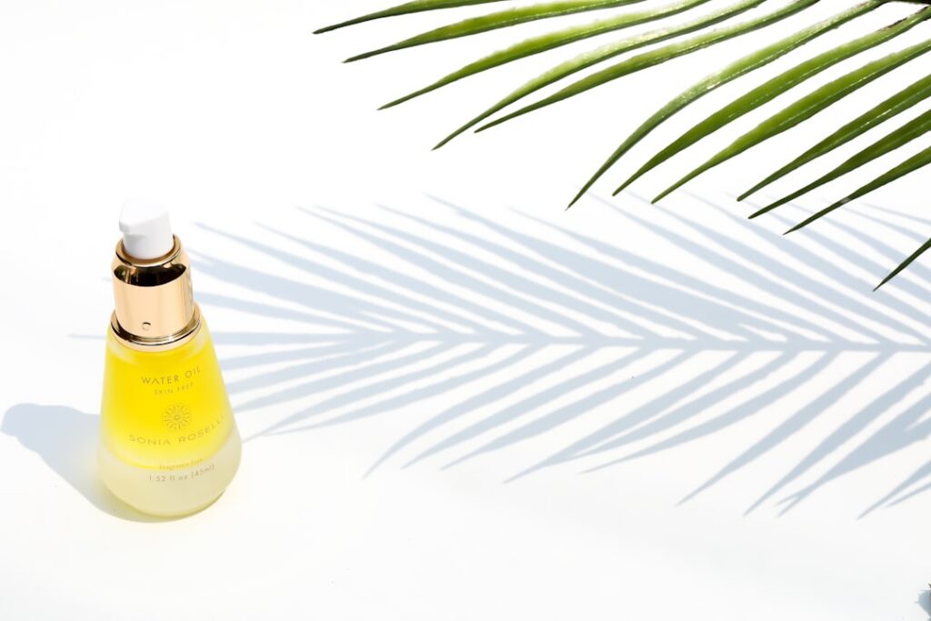 A close-up of a glass dropper bottle filled with a golden oil with a bottle of Johnson s Baby Oil and various natural in