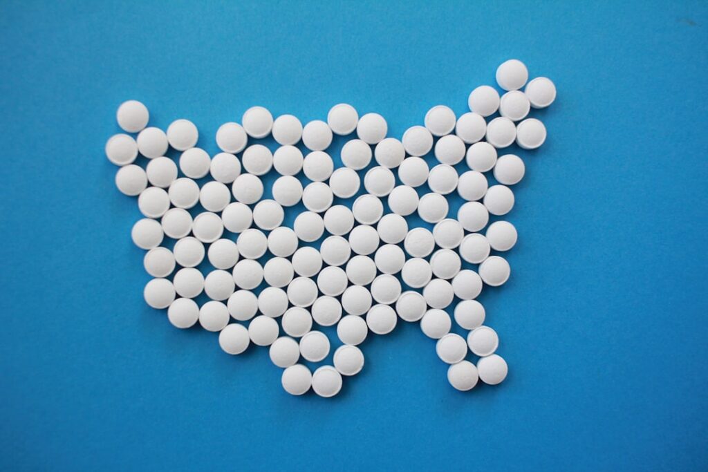 Crushing aspirin tablets in a small bowl with a spoon with a few drops of water