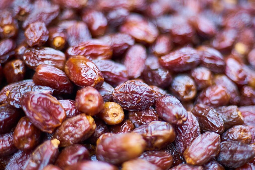 A close-up of several ripe plump Medjool dates on a rustic wooden plate emphasizing their rich color and soft texture