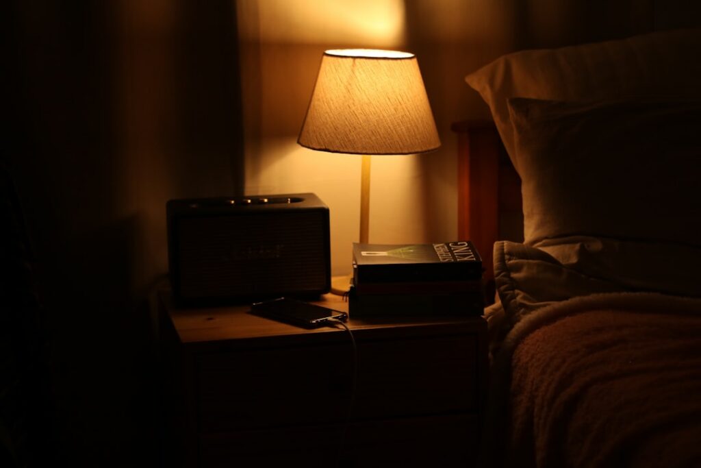 A person holding a small bowl of dates next to a glass of water on a bedside table creating a serene evening scene