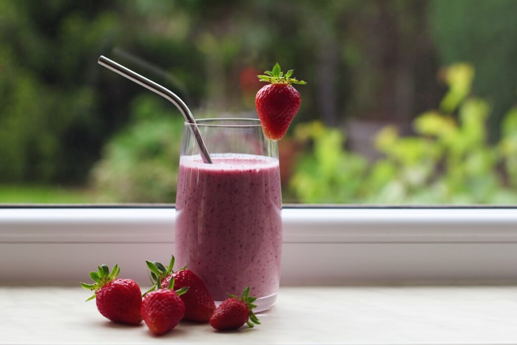 A vibrant creamy berry collagen drink in a clear glass garnished with fresh mixed berries chia seeds and a sprig of mint