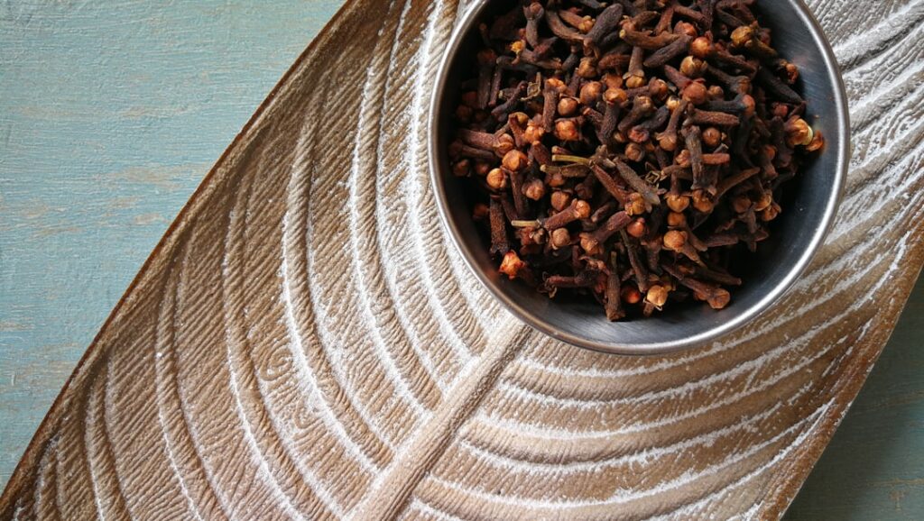 Small piles of white rice brown rice and whole dried cloves laid out ready for use