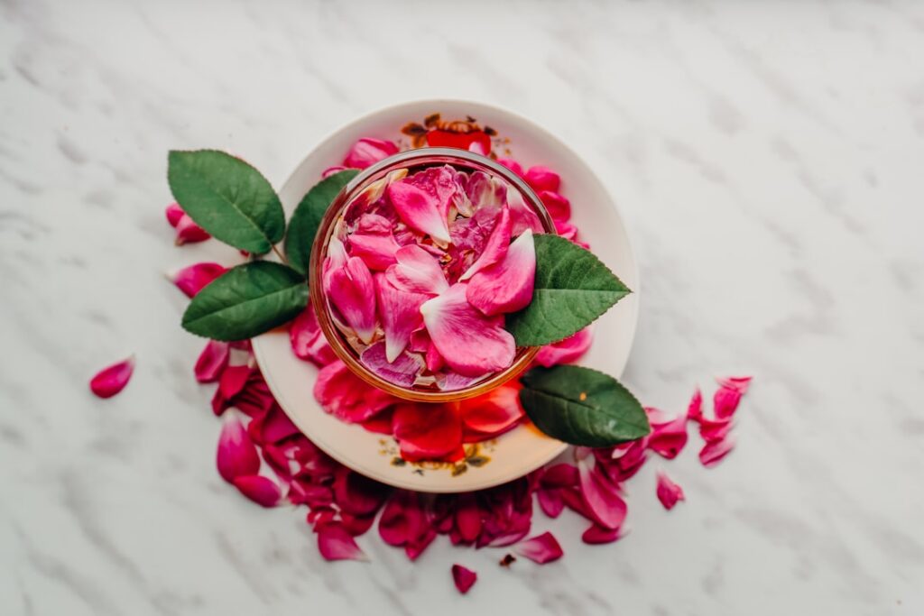 A collection of natural ingredients a bottle of rose water a small bowl of dried cloves and a small bowl of yellow turme