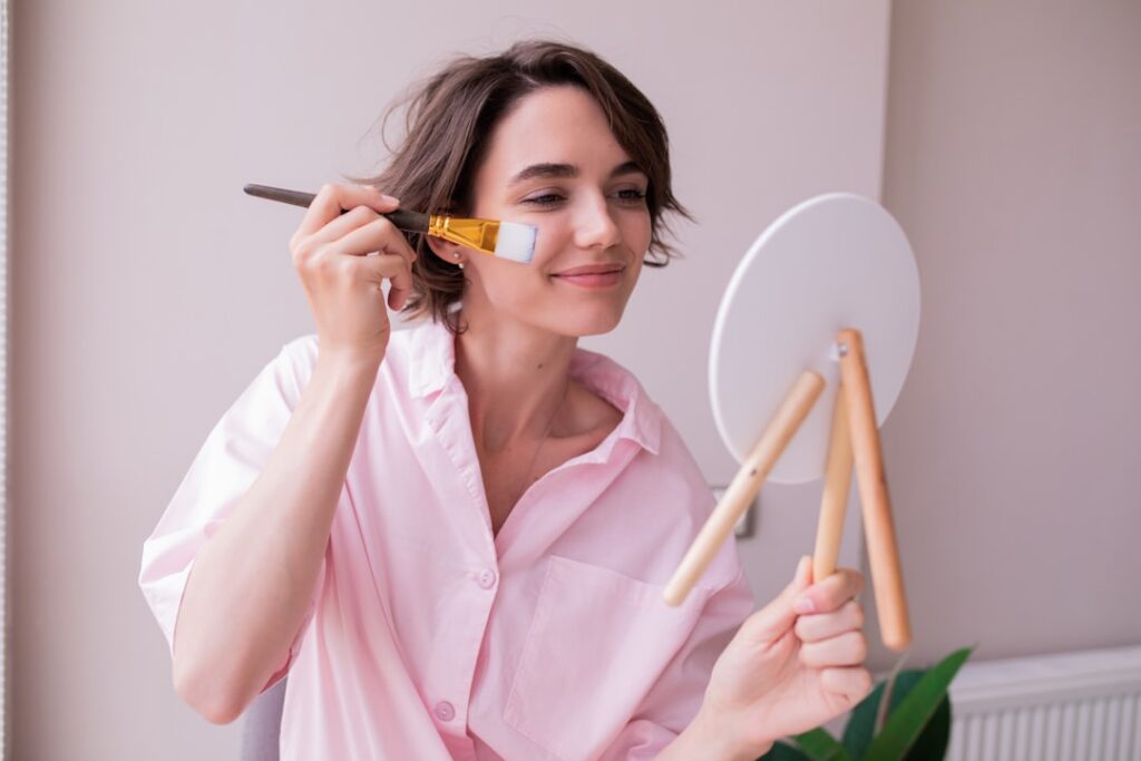 A woman gently applying a DIY face mask with a brush to her clean face looking relaxed and radiant Her eyes are closed o