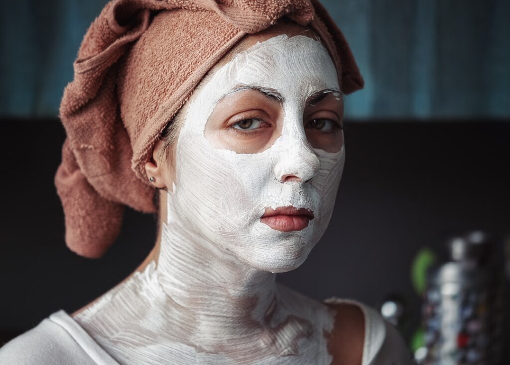 A person gently peeling off a dry DIY Vaseline and egg white mask from their chin upwards revealing smoother skin undern