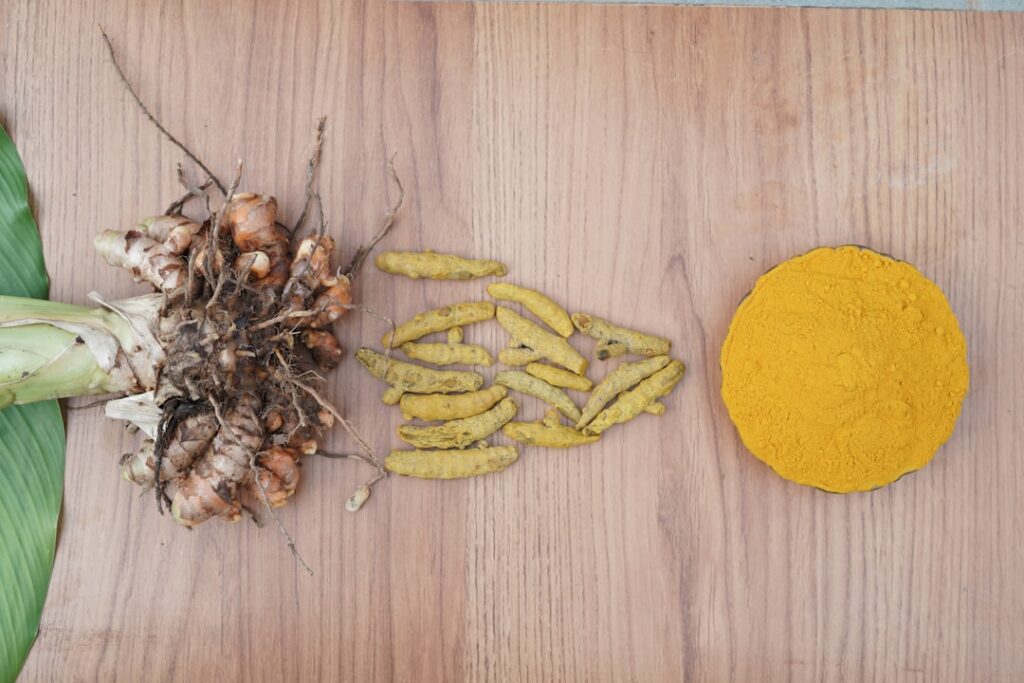 Hands mixing turmeric powder into Vaseline in a small jar