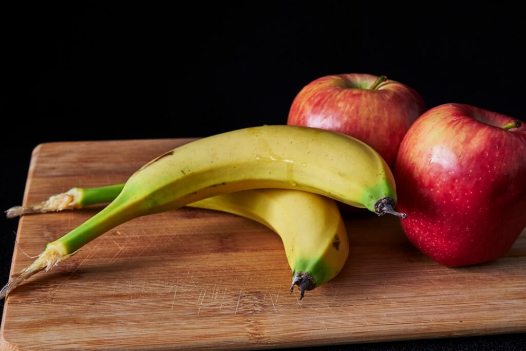 A vibrant infographic comparing a banana and an apple side-by-side highlighting key nutritional facts like potassium fib