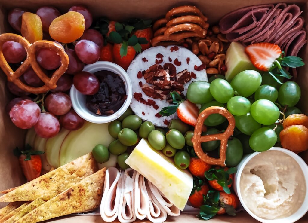 A colorful array of healthy snack options laid out such as apple slices carrots hummus almonds and blueberries