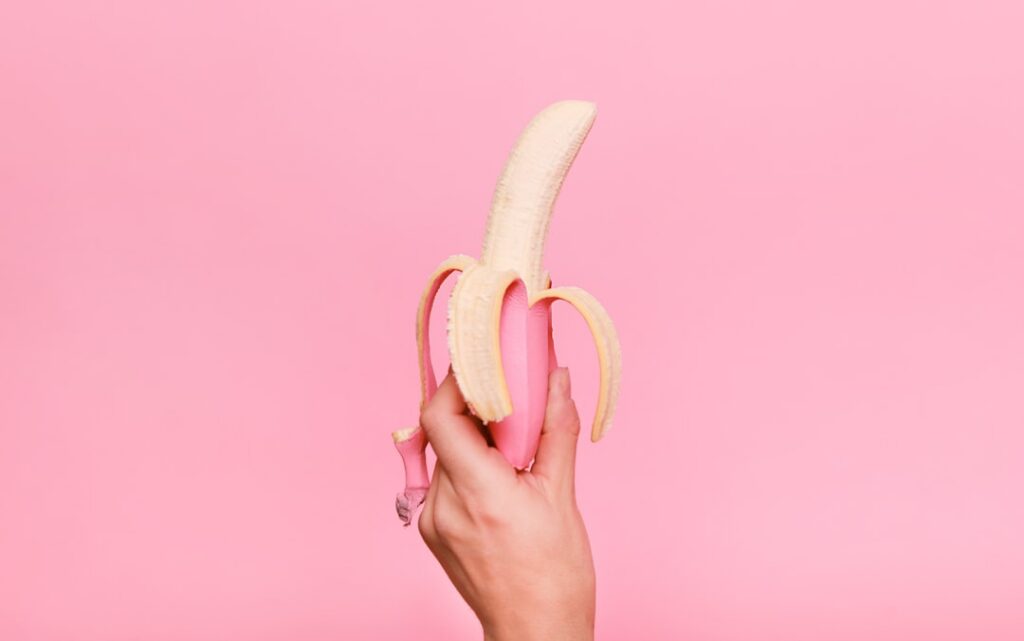 A person thoughtfully considering a banana as a nighttime snack perhaps in a kitchen