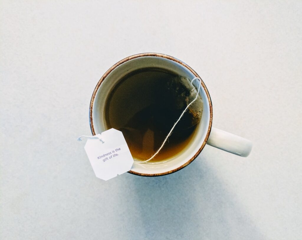 A clear glass mug filled with freshly prepared purslane tea with some purslane leaves still visible at the bottom placed