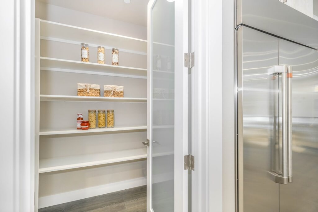 An organized well-stocked kitchen pantry and refrigerator filled with healthy food staples like fresh produce grains leg