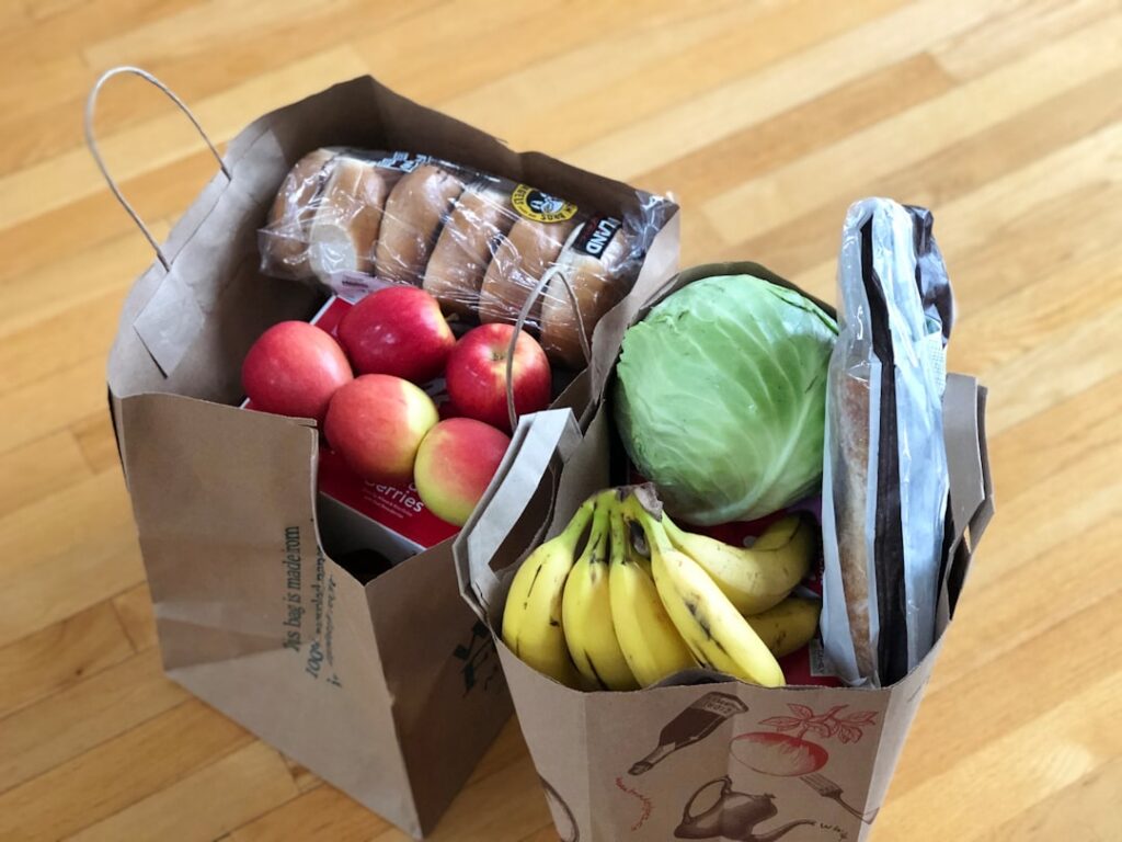 A person looking strong and healthy smiling while holding a grocery bag filled with affordable healthy ingredients like 
