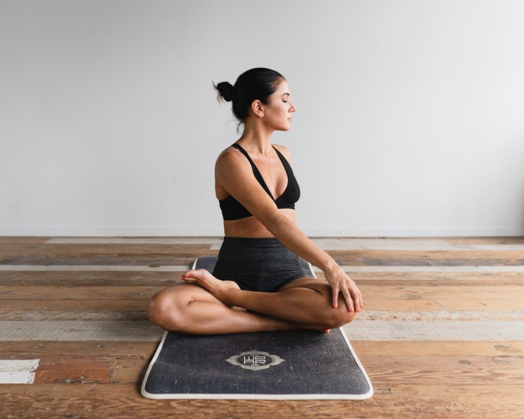 A woman gracefully performing a yoga pose that engages the core and waist muscles set in a bright tranquil studio with n