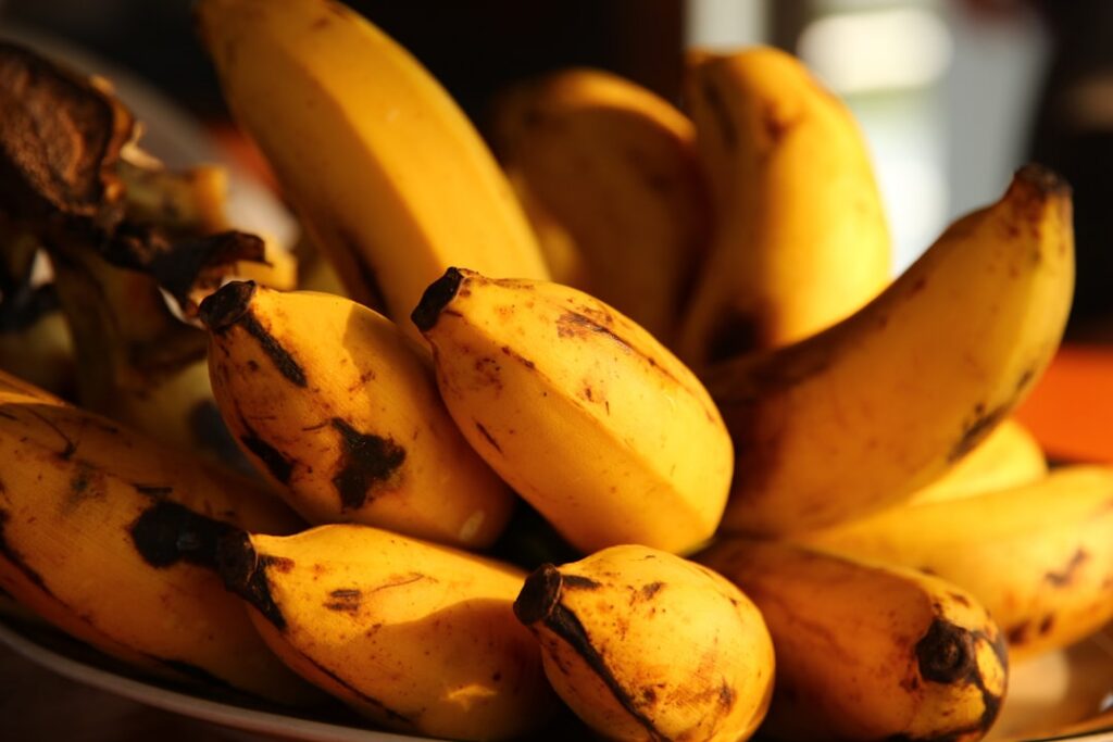 A close-up of a jar filled with chopped banana peels soaking in water with small bubbles visible indicating fermentation