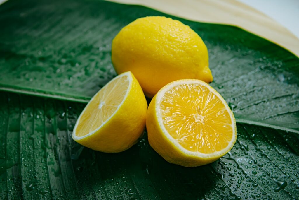 A vibrant golden turmeric and lemon drink in a glass garnished with fresh lemon slices and a sprinkle of turmeric agains