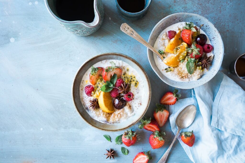 A vibrant bowl of cottage cheese topped with fresh berries sliced peaches and a sprinkle of nuts presented on a light-co