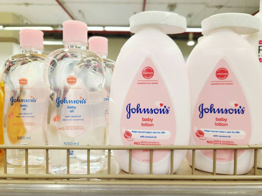 A glass bottle of baby oil and a few vitamin E capsules arranged on an elegant surface suggesting a simple natural beaut