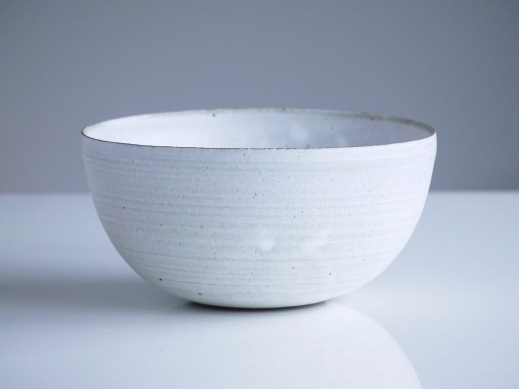 A clean empty ceramic bowl on a rustic wooden table with soft natural light symbolizing potential and a fresh start for 