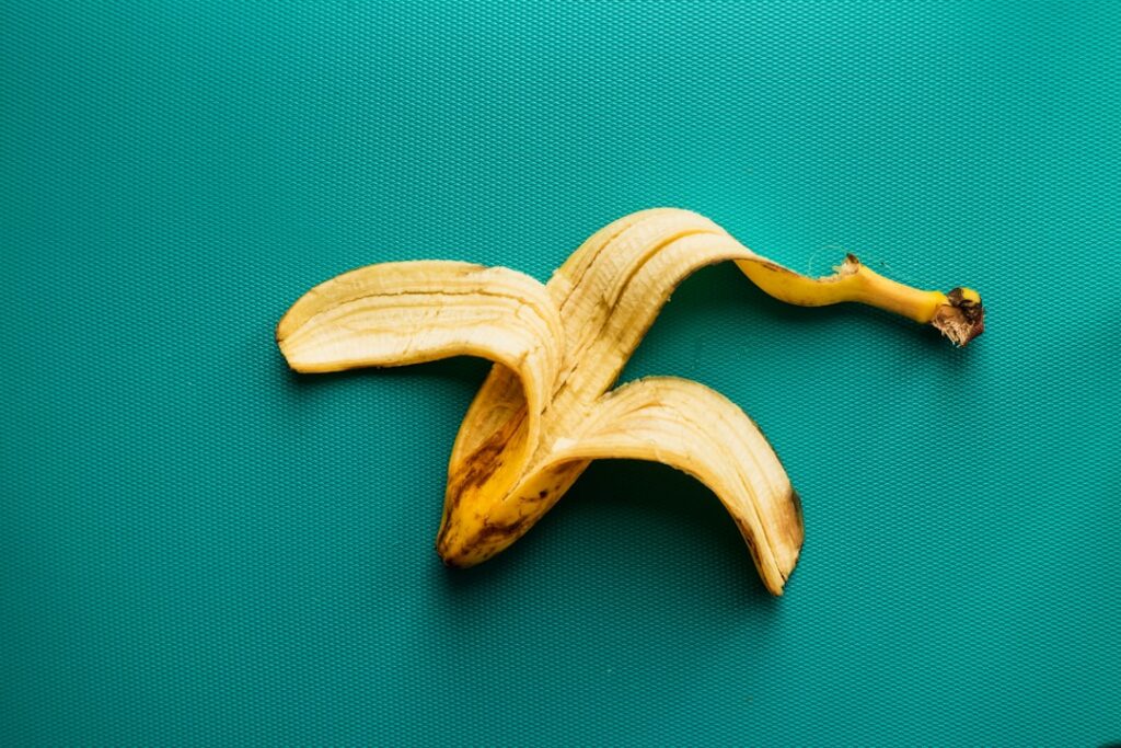 A close-up of several banana peels some whole and some chopped lying on a wooden cutting board with a small gardening tr