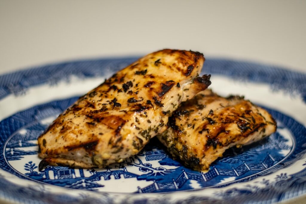 A cooked salmon fillet seasoned with fresh dill parsley and lemon slices served on a white plate Small glass bowls with 