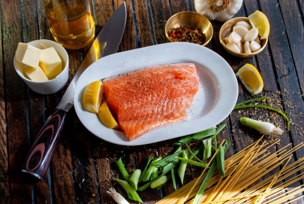 A cooked salmon fillet coated in a glossy honey garlic glaze served on a white plate with lemon wedges Small glass bowls