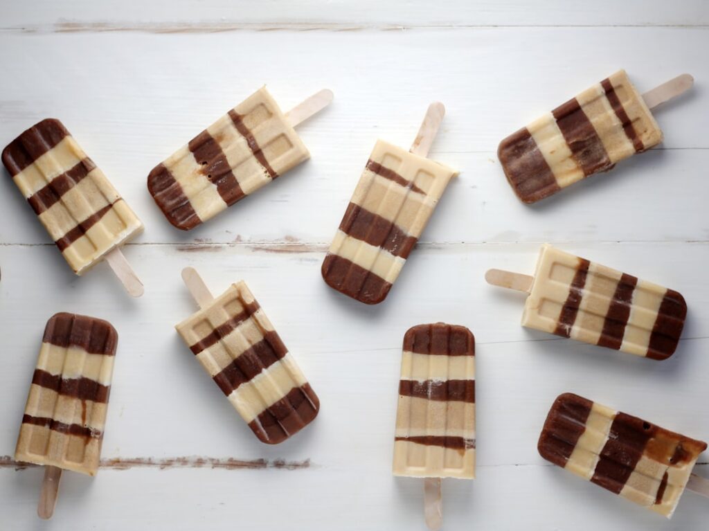 Close-up of dark brown Chocolate Ice Candy in a clear plastic bag with chocolate chips and cocoa powder scattered around