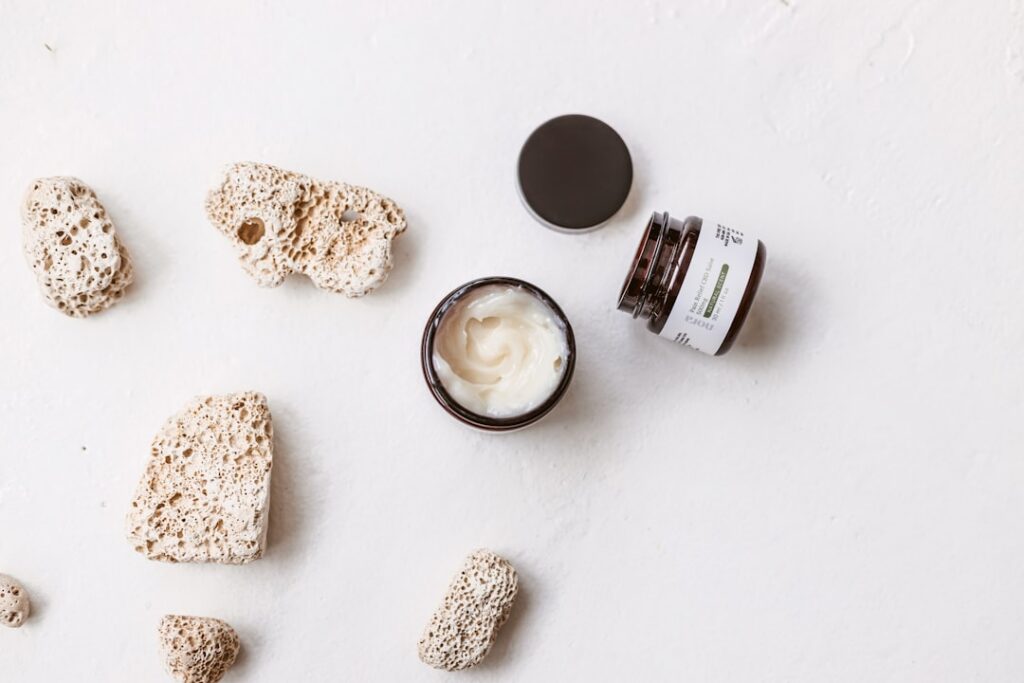 A small glass jar filled with the homemade potato rice under-eye cream placed on a rustic wooden table with soft lightin