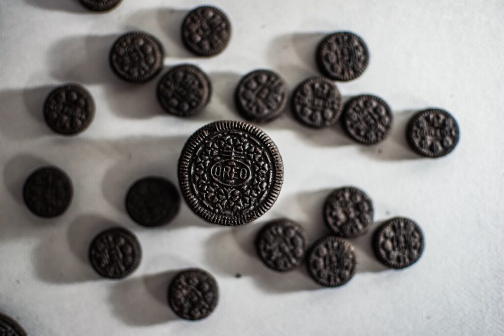 Close-up of spherical Oreo truffles coated in crushed Oreo cookies and drizzled with white chocolate on a white plate On