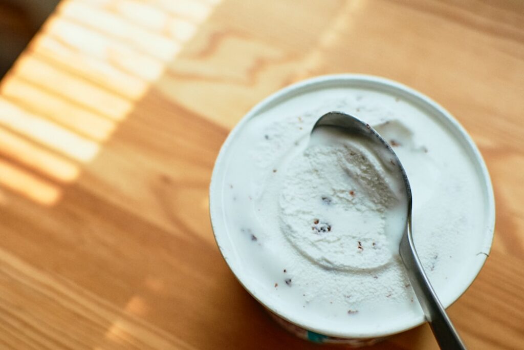 A spoonful of the finely ground seed blend being added to a bowl of yogurt with berries