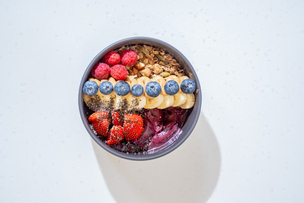 A vibrant colorful smoothie bowl topped with fresh berries nuts and seeds suggesting brain-boosting nutrients